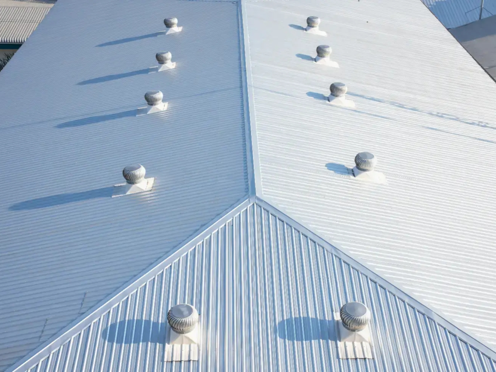 Light-colored commercial metal roof with vents and roof seams